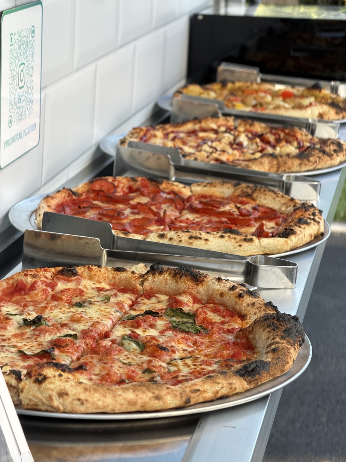 Fresh Whisk And Pickle pizzas laid out for guests at an event