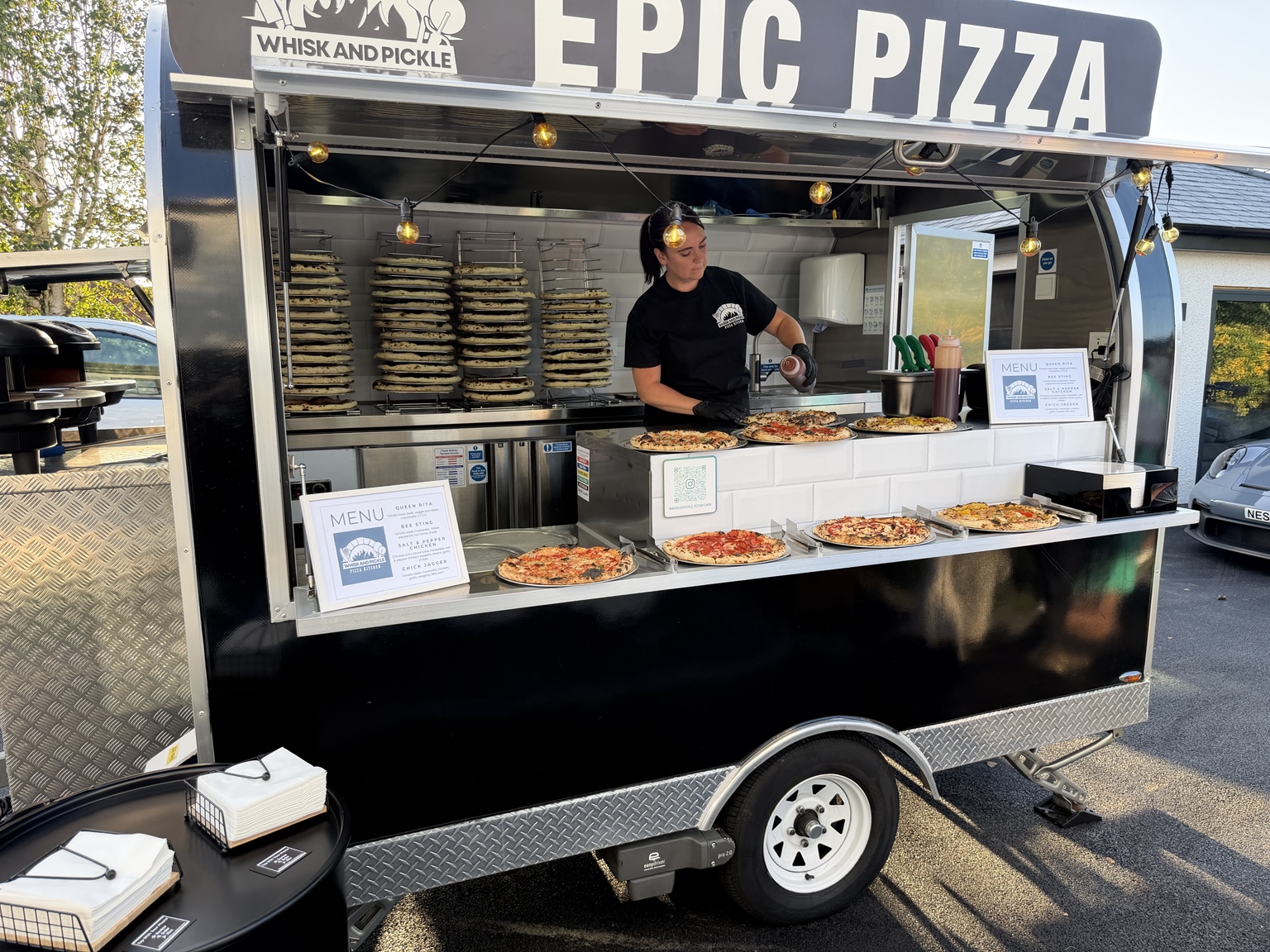 Whisk And Pickle team serving pizza from the mobile trailer